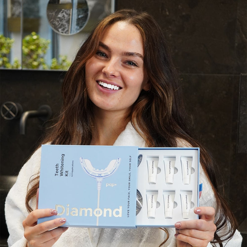 Nainen, jolla on puhelin PAP+ hampaiden valkaisusetti Diamond Smile